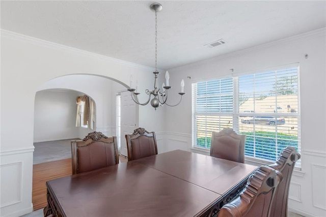 11354 Conner Ct, Hampton, GA 30228 - dining area with a chandelier, arched walkways, ornamental molding, a decorative wall, and wainscoting