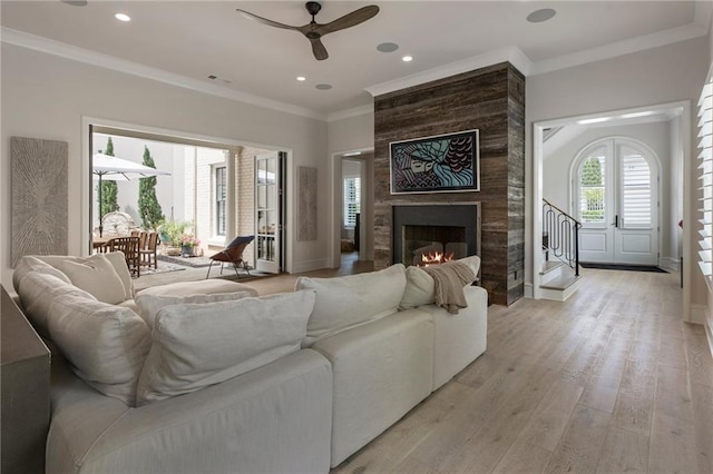 living room featuring crown molding, light wood finished floors, a ceiling fan, baseboards, and visible vents
