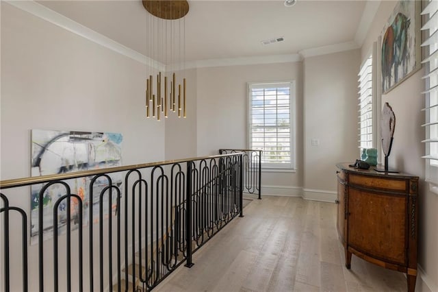 hallway with baseboards, an upstairs landing, wood finished floors, visible vents, and ornamental molding