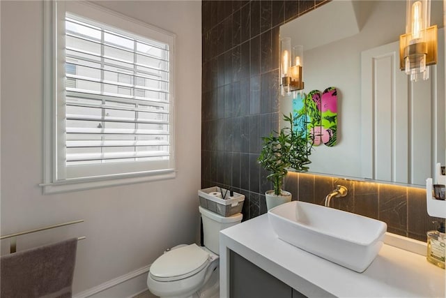half bathroom with vanity, backsplash, toilet, and a wealth of natural light