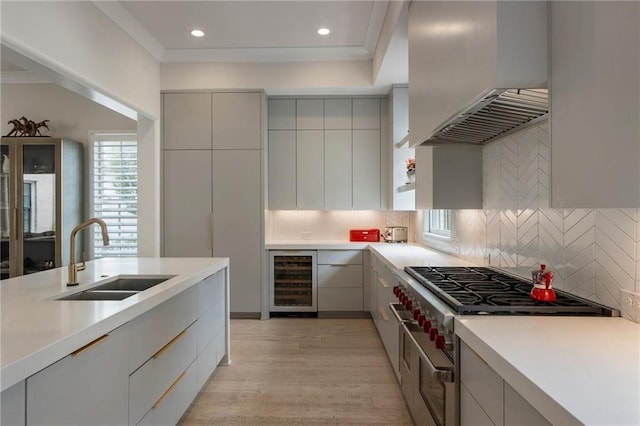 kitchen with wine cooler, modern cabinets, custom exhaust hood, and a sink