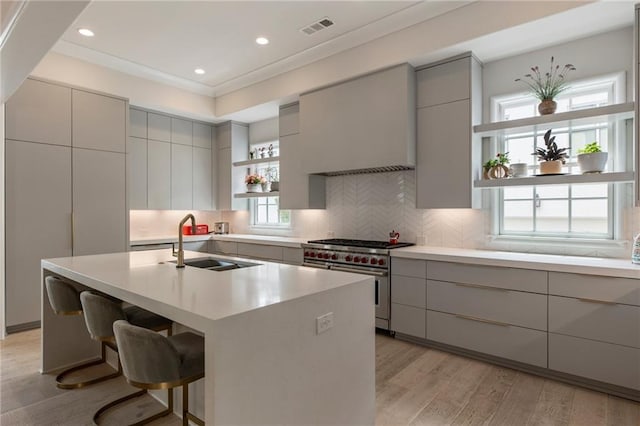 kitchen featuring visible vents, modern cabinets, a sink, high end stainless steel range oven, and gray cabinetry