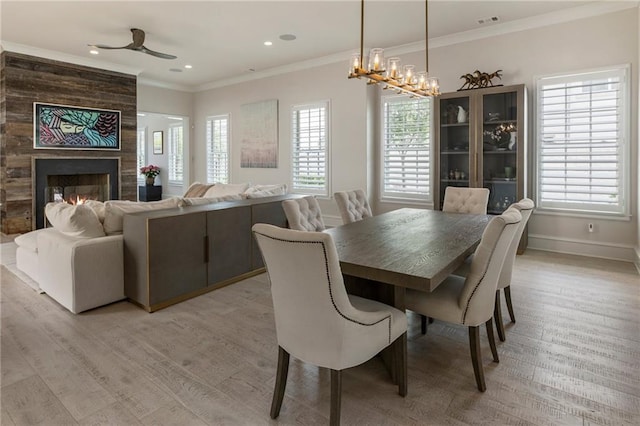 dining room with crown molding, baseboards, a multi sided fireplace, and light wood-type flooring