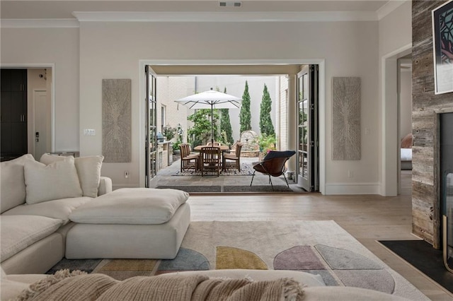 living area with crown molding, visible vents, wood finished floors, a fireplace, and baseboards