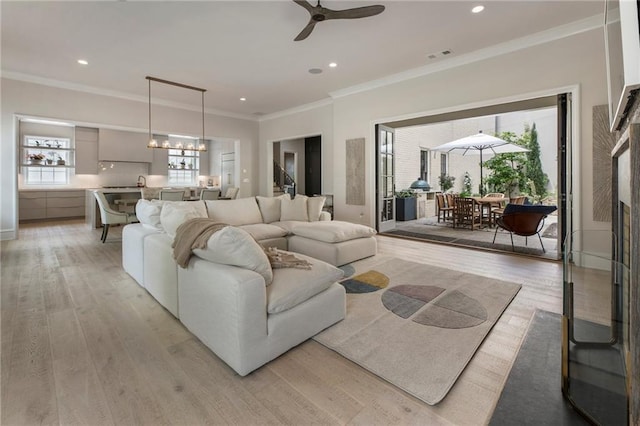 living area featuring recessed lighting, ceiling fan, ornamental molding, and light wood-style flooring