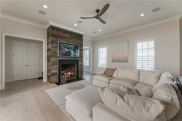living area with light wood-type flooring, a ceiling fan, plenty of natural light, and a fireplace