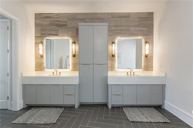 bathroom featuring baseboards, a sink, and two vanities