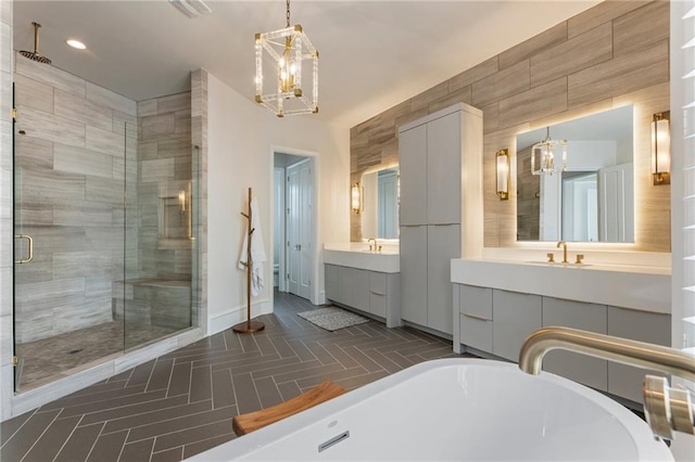 full bathroom featuring baseboards, a soaking tub, a stall shower, and a notable chandelier