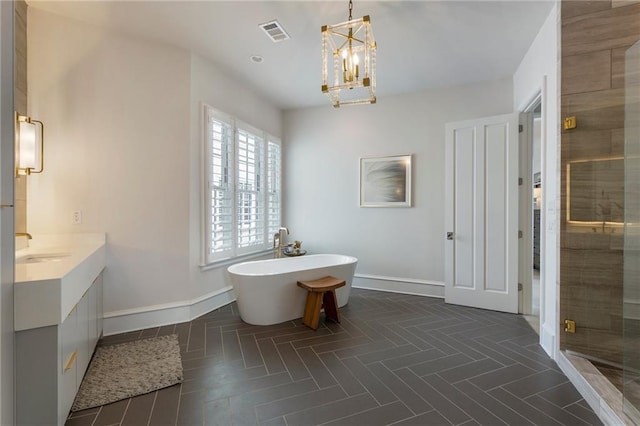 bathroom with visible vents, baseboards, a freestanding tub, and an inviting chandelier