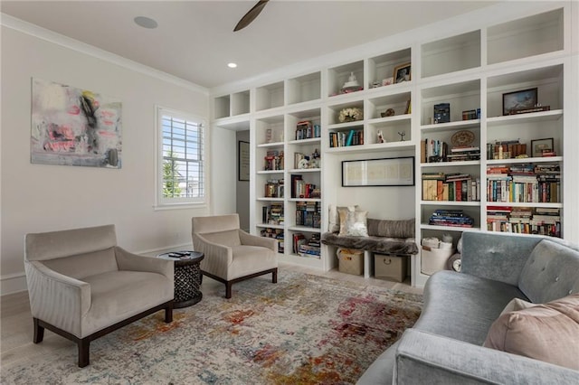 living area with baseboards, ornamental molding, and ceiling fan