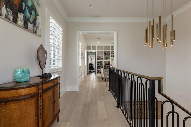 hall with baseboards, visible vents, ornamental molding, and light wood-type flooring