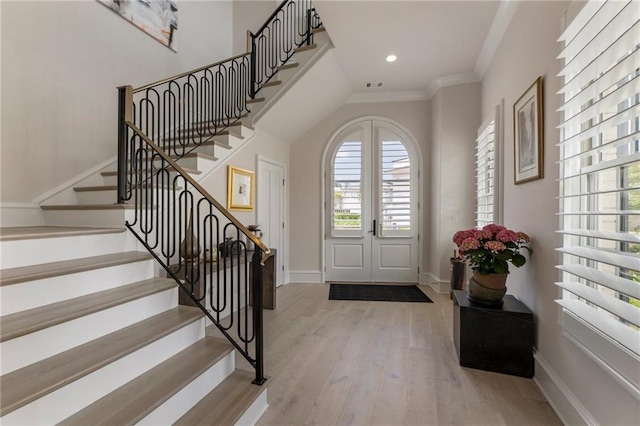 foyer entrance featuring crown molding, baseboards, wood finished floors, and stairway