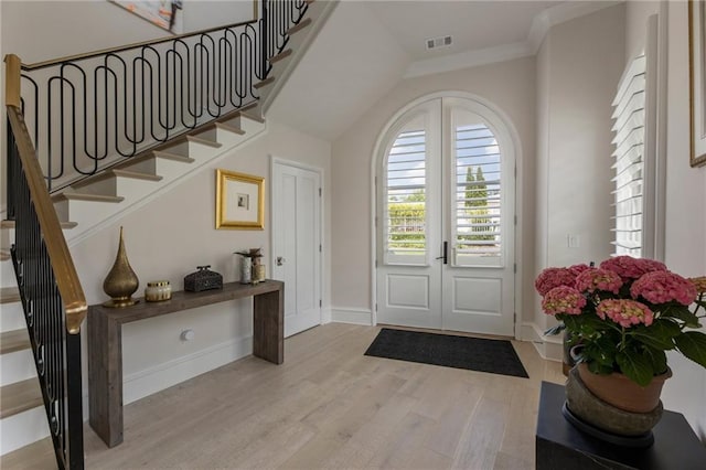 foyer entrance with baseboards, light wood finished floors, stairs, and visible vents