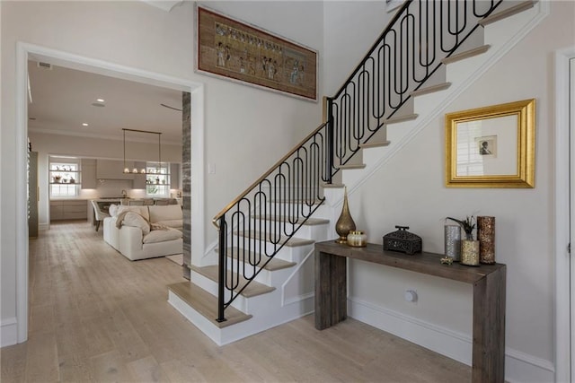 staircase with crown molding, baseboards, and wood finished floors
