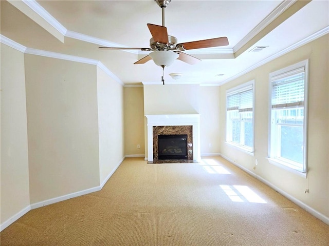 unfurnished living room featuring crown molding, ceiling fan, carpet flooring, and a high end fireplace