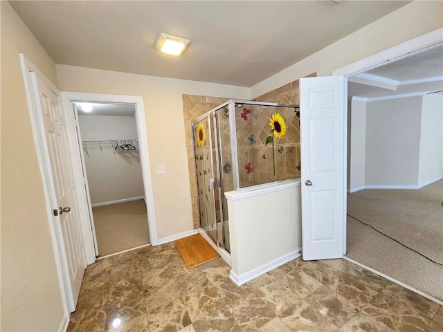 full bath featuring a walk in closet, baseboards, and a stall shower
