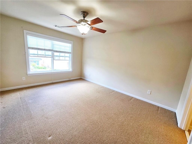 spare room featuring ceiling fan, baseboards, and light carpet
