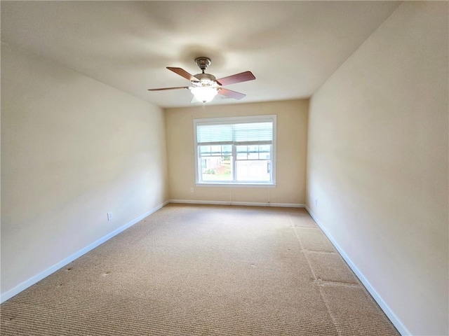 spare room featuring light carpet, a ceiling fan, and baseboards