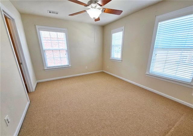 unfurnished room featuring light carpet, baseboards, visible vents, and a ceiling fan