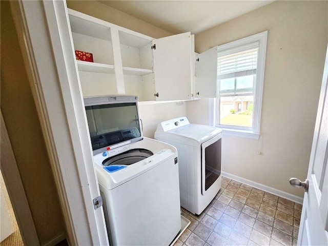 washroom featuring cabinet space, baseboards, and washer and clothes dryer