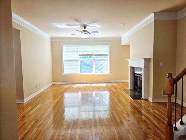 unfurnished living room featuring a ceiling fan, ornamental molding, baseboards, light wood-style flooring, and a tiled fireplace