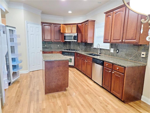 kitchen featuring light wood-style floors, a kitchen island, appliances with stainless steel finishes, and a sink