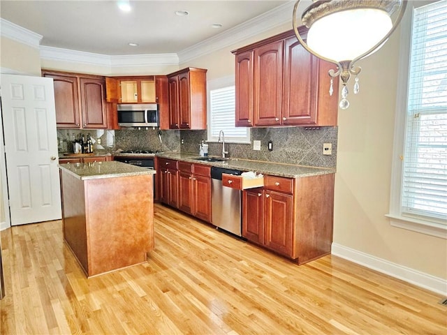 kitchen featuring a center island, appliances with stainless steel finishes, a sink, and light wood-type flooring