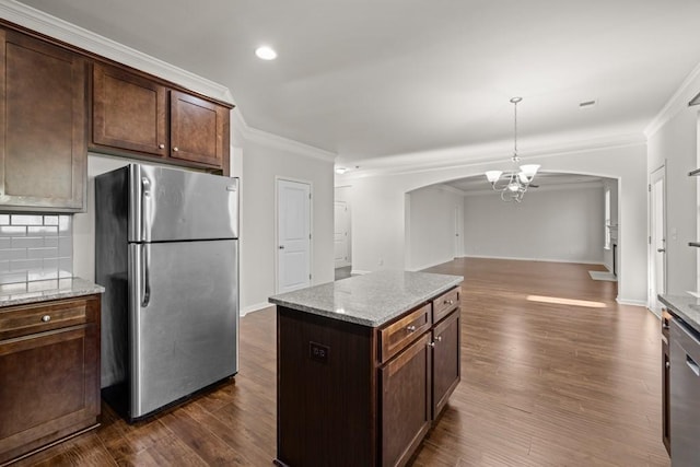 kitchen featuring dark wood-style flooring, appliances with stainless steel finishes, open floor plan, and ornamental molding