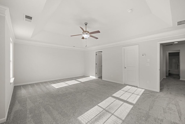 carpeted spare room featuring a tray ceiling, baseboards, and visible vents