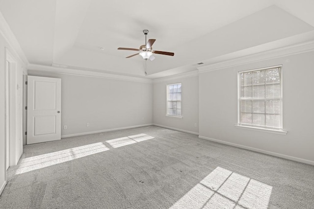 carpeted spare room with baseboards, a tray ceiling, and ornamental molding