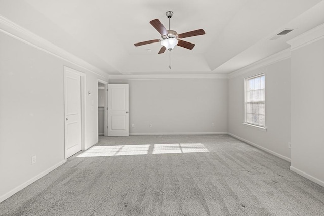 unfurnished room featuring crown molding, ceiling fan, baseboards, a tray ceiling, and light carpet