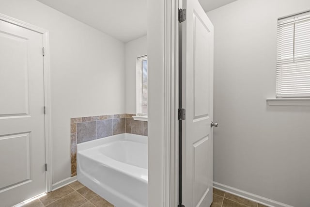 bathroom with tile patterned flooring, a garden tub, and baseboards