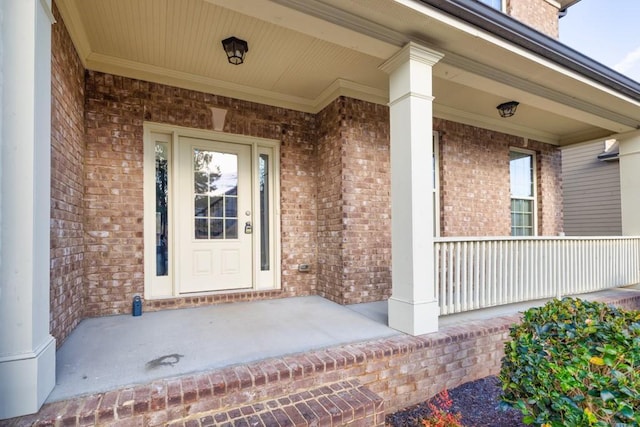 entrance to property with a porch and brick siding