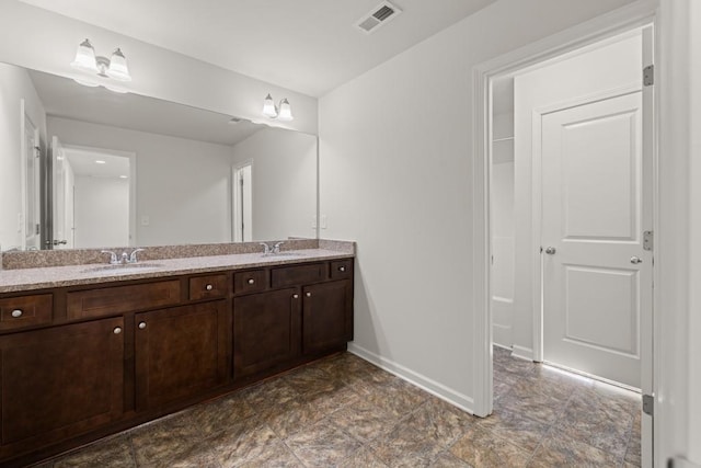 full bath with double vanity, visible vents, baseboards, and a sink