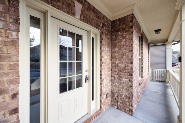 doorway to property with brick siding and covered porch