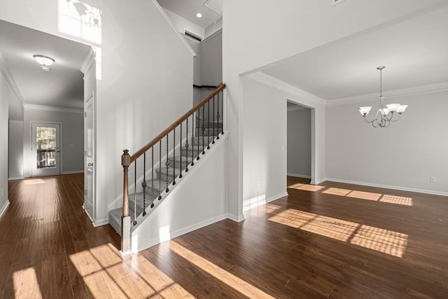 foyer entrance featuring a notable chandelier, ornamental molding, hardwood / wood-style flooring, stairway, and baseboards