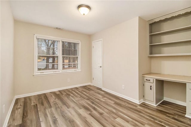 interior space with wood-type flooring and built in desk