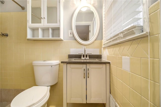 bathroom with toilet, tile walls, and vanity