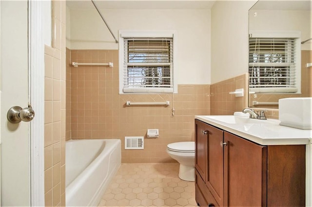 full bathroom with tile patterned flooring, toilet, washtub / shower combination, tile walls, and vanity