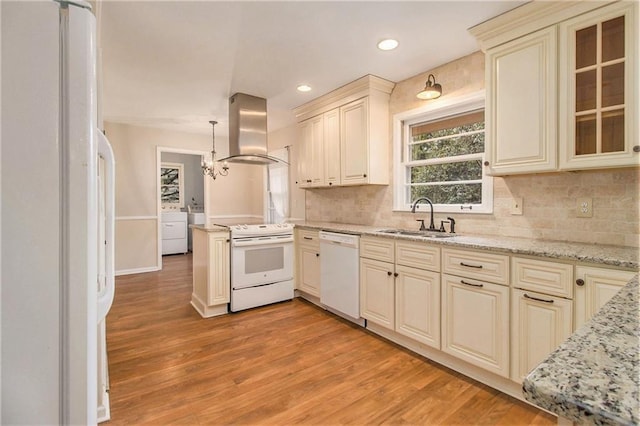 kitchen featuring white appliances, sink, island exhaust hood, cream cabinetry, and hanging light fixtures