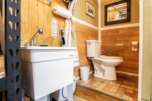 bathroom featuring wooden walls, vanity, toilet, and tile floors