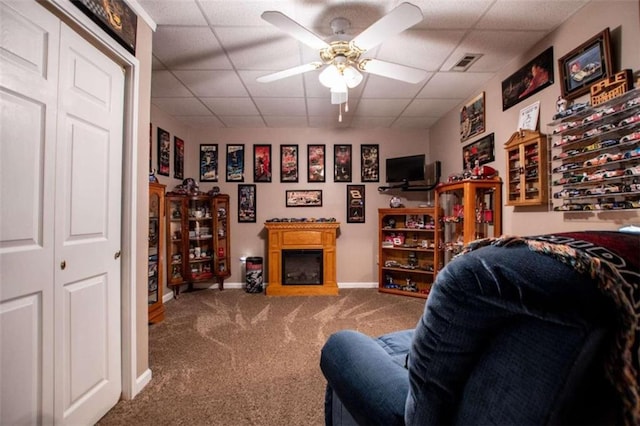 living room featuring carpet floors, ceiling fan, and a drop ceiling