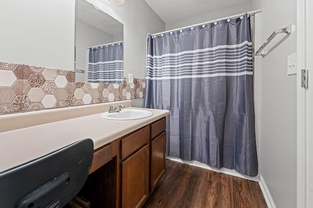 bathroom with vanity, hardwood / wood-style floors, tasteful backsplash, and a textured ceiling