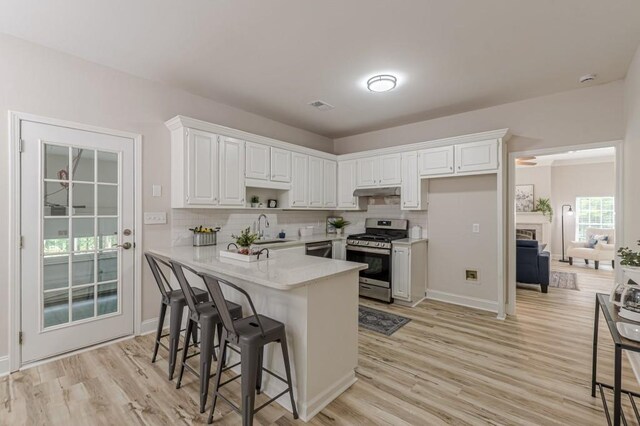 3329 Walt Stephens Rd, Stockbridge, GA 30281 - kitchen featuring stainless steel appliances, a peninsula, light wood-style flooring, white cabinets, and a kitchen bar