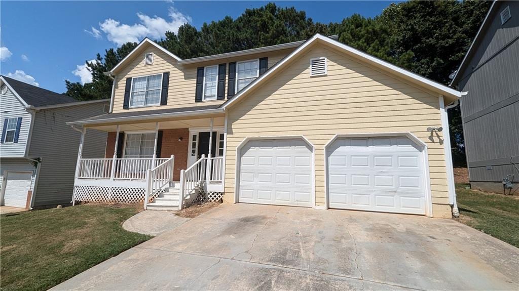 view of front of property with a garage, a front lawn, and covered porch