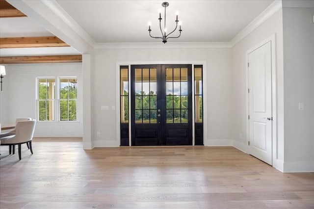 foyer entrance featuring a chandelier, french doors, wood finished floors, and ornamental molding