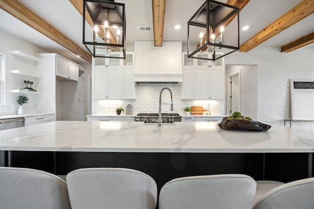 kitchen featuring light stone counters, visible vents, white cabinetry, tasteful backsplash, and a large island with sink