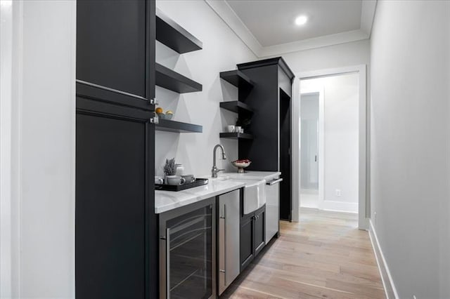 kitchen featuring wine cooler, ornamental molding, dark cabinets, light wood-style floors, and open shelves