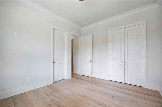 unfurnished bedroom with light wood-style floors, a closet, crown molding, and baseboards