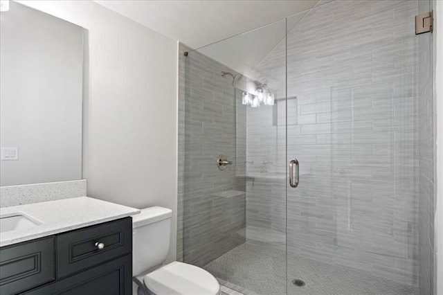 full bathroom featuring a stall shower, vanity, and toilet